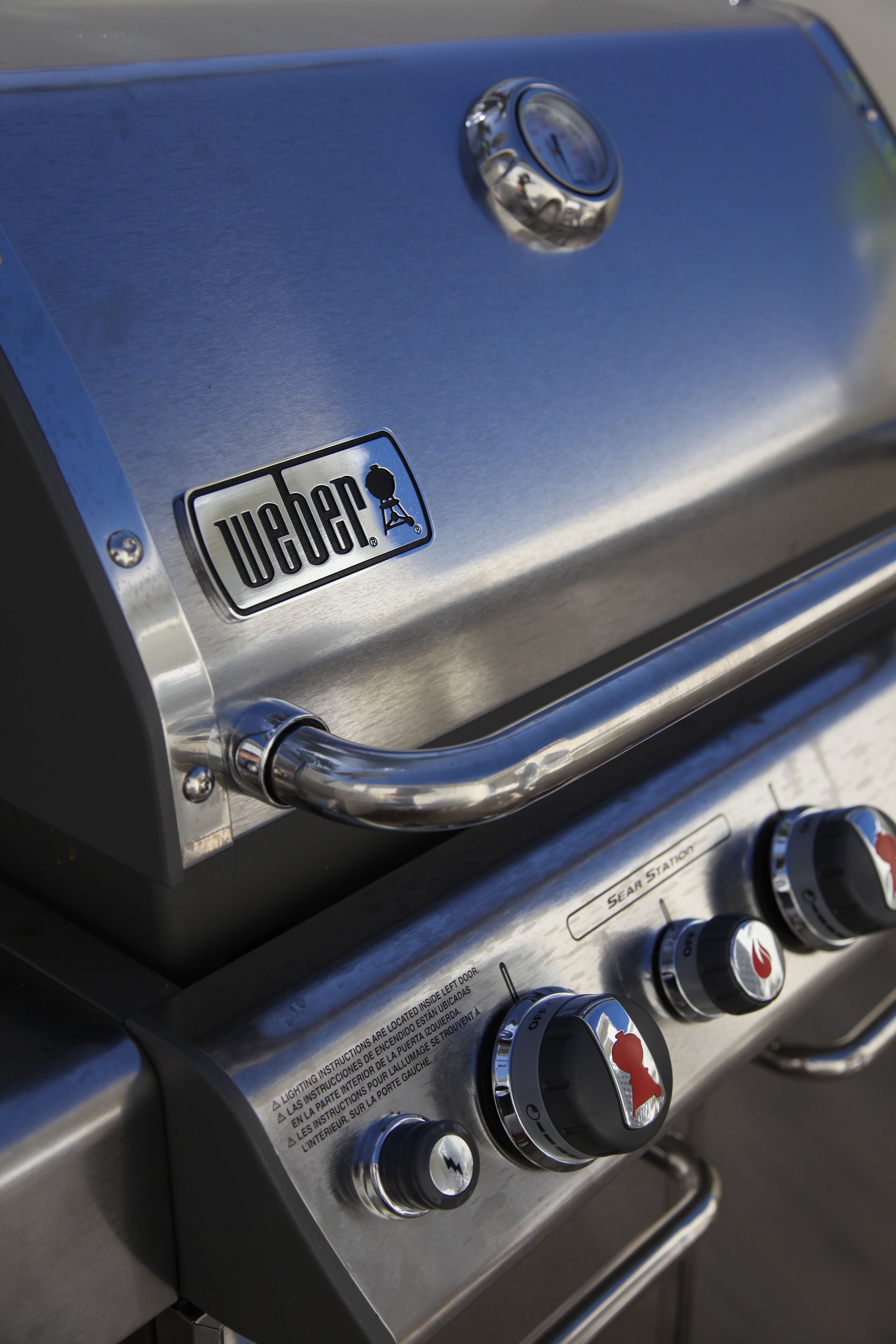 A Weber grill with a handle and three control knobs.