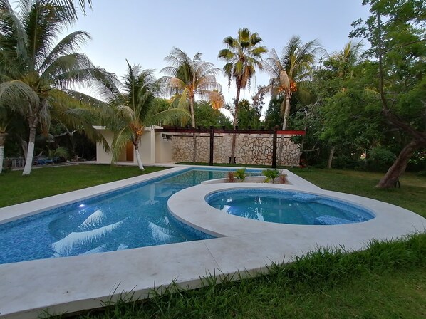A swimming pool with a stone wall and palm trees in the background.