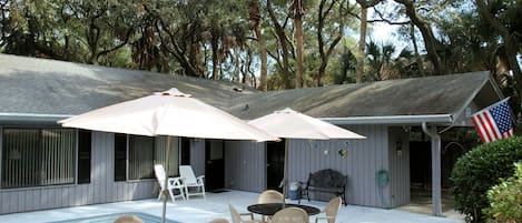 A poolside area with a table and chairs, an American flag, and a covered patio with umbrellas.
