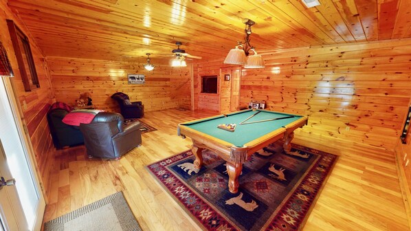 A cozy room with a pool table, a leather sofa, and a rug. - Location!!! Country Charm Lodge - Hot tub - Game room - Large Porch- Picnic Area (Pigeon Forge)