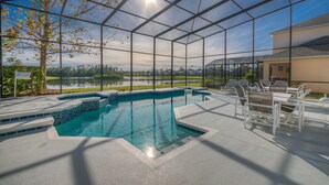 A pool area with a clear view of the lake, surrounded by a glass enclosure, and furnished with outdoor seating. - Lakeside house, huge south facing pool with spa,  lake view, Disney at 8 miles (Kissimmee)