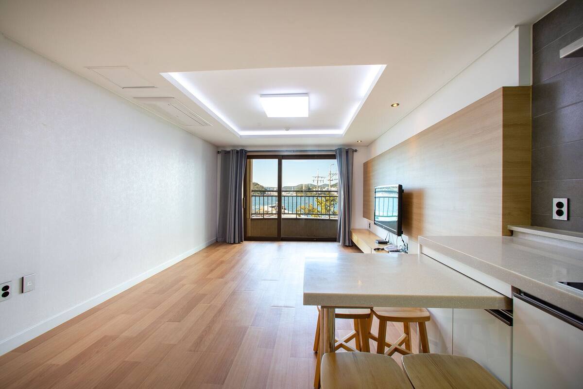 Een moderne keuken met een groot schiereiland, een eethoek en uitzicht op een waterkant.