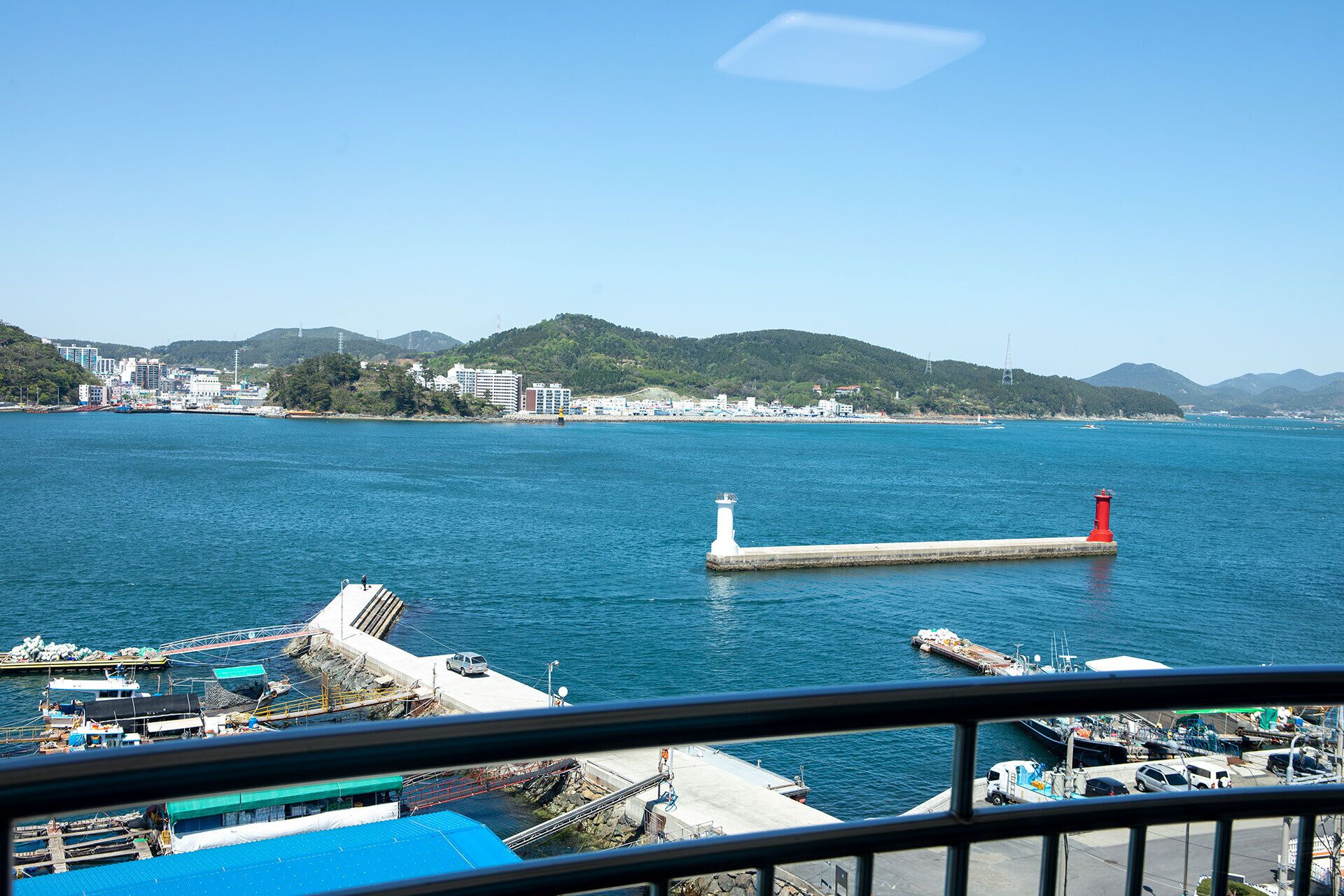 Vista costera con muelle, barcos y un faro.