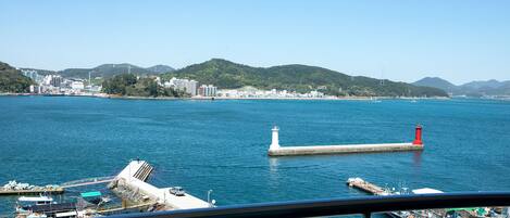 Vista costera con muelle, barcos y un faro.