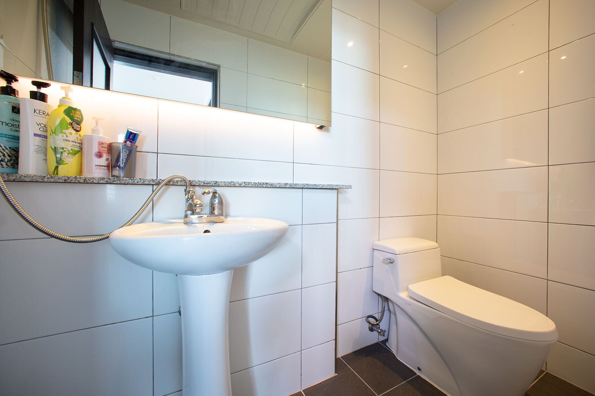 A bathroom with a white sink, a toilet, and a mirror above the sink.