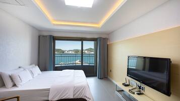 Una camera d'hotel con un letto, una TV e vista mare.