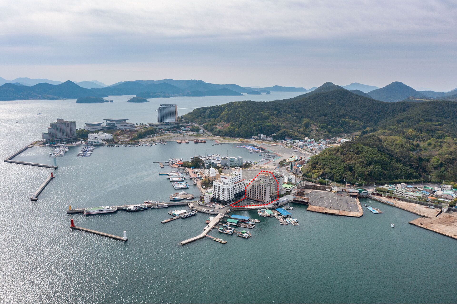 Vista aérea de una marina costera con varios muelles, barcos y edificios.