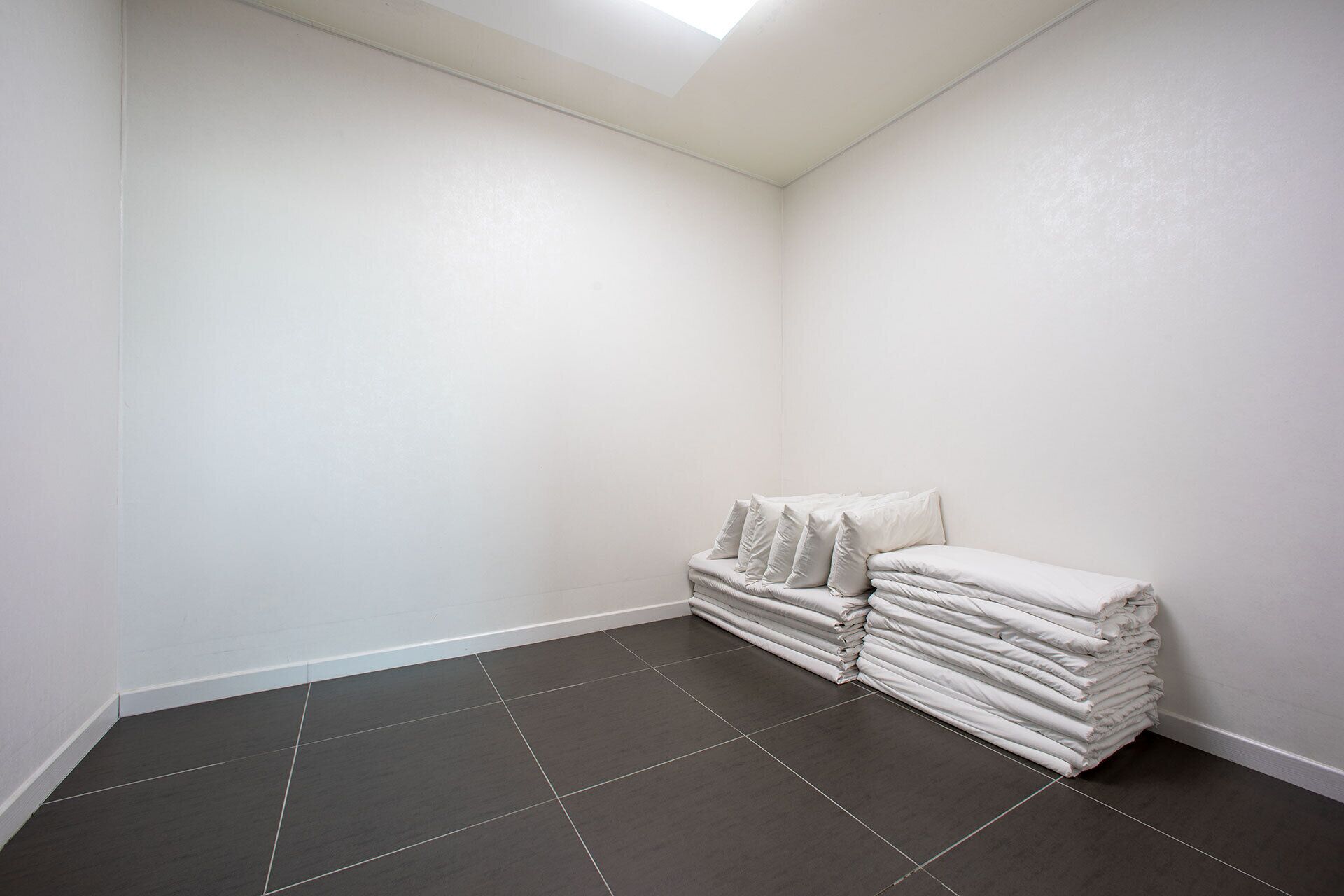 Habitación en esquina con paredes blancas y piso de baldosas grises oscuras.