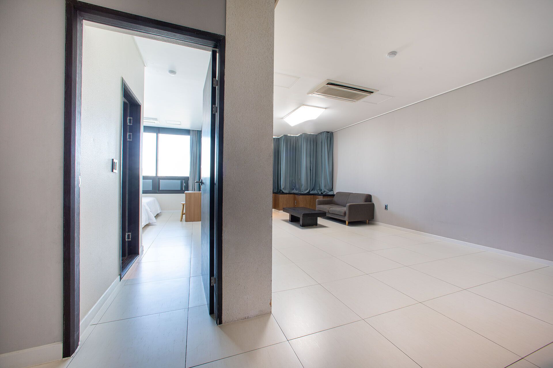 A spacious hotel room with a large open area, a sofa, and a desk.