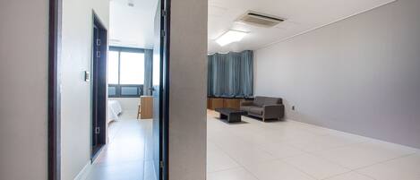 A spacious hotel room with a large open area, a sofa, and a desk.