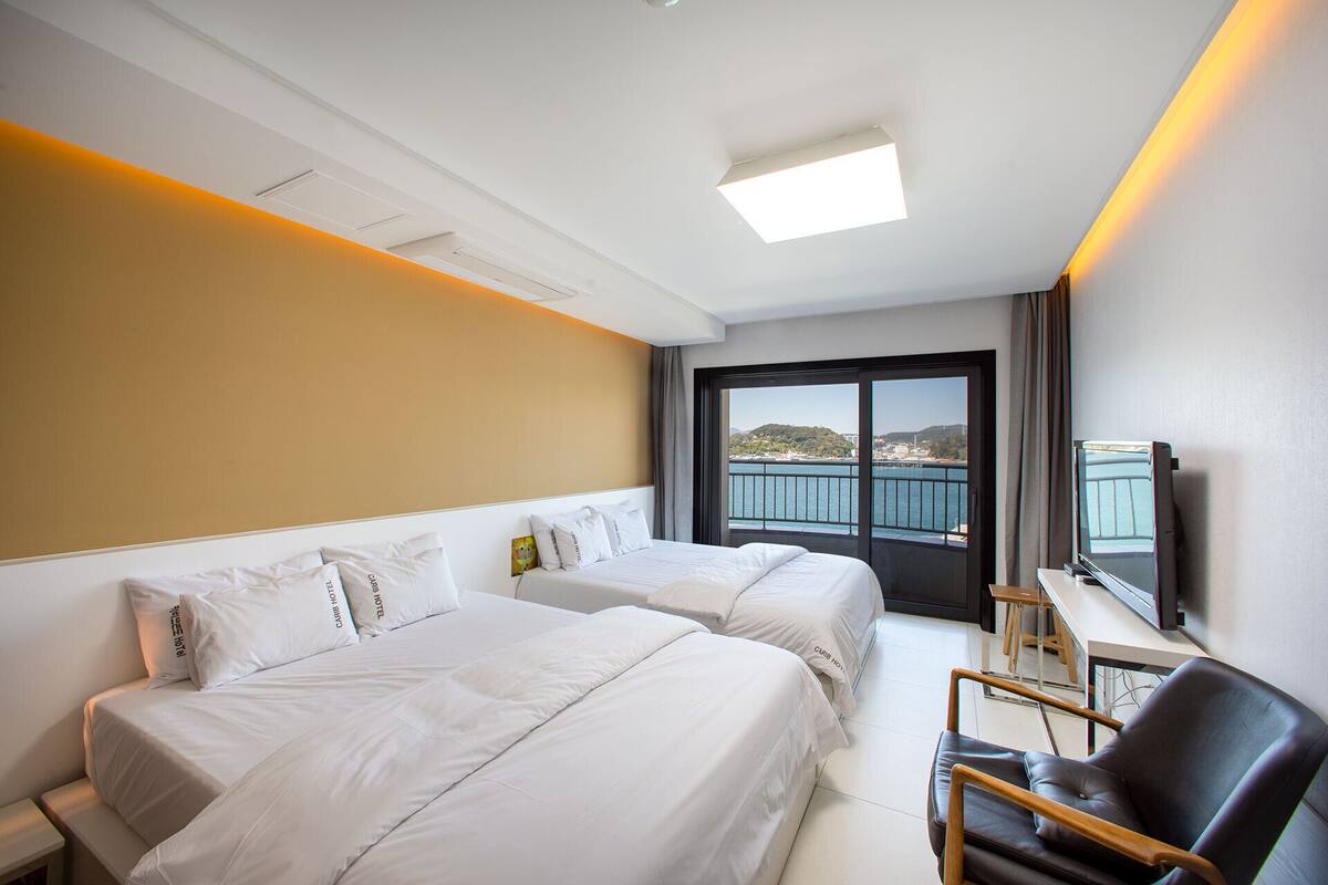 Een hotelkamer met twee bedden, een televisie en uitzicht op een waterpartij.