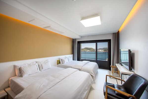 Een hotelkamer met twee bedden, een televisie en uitzicht op een waterpartij.