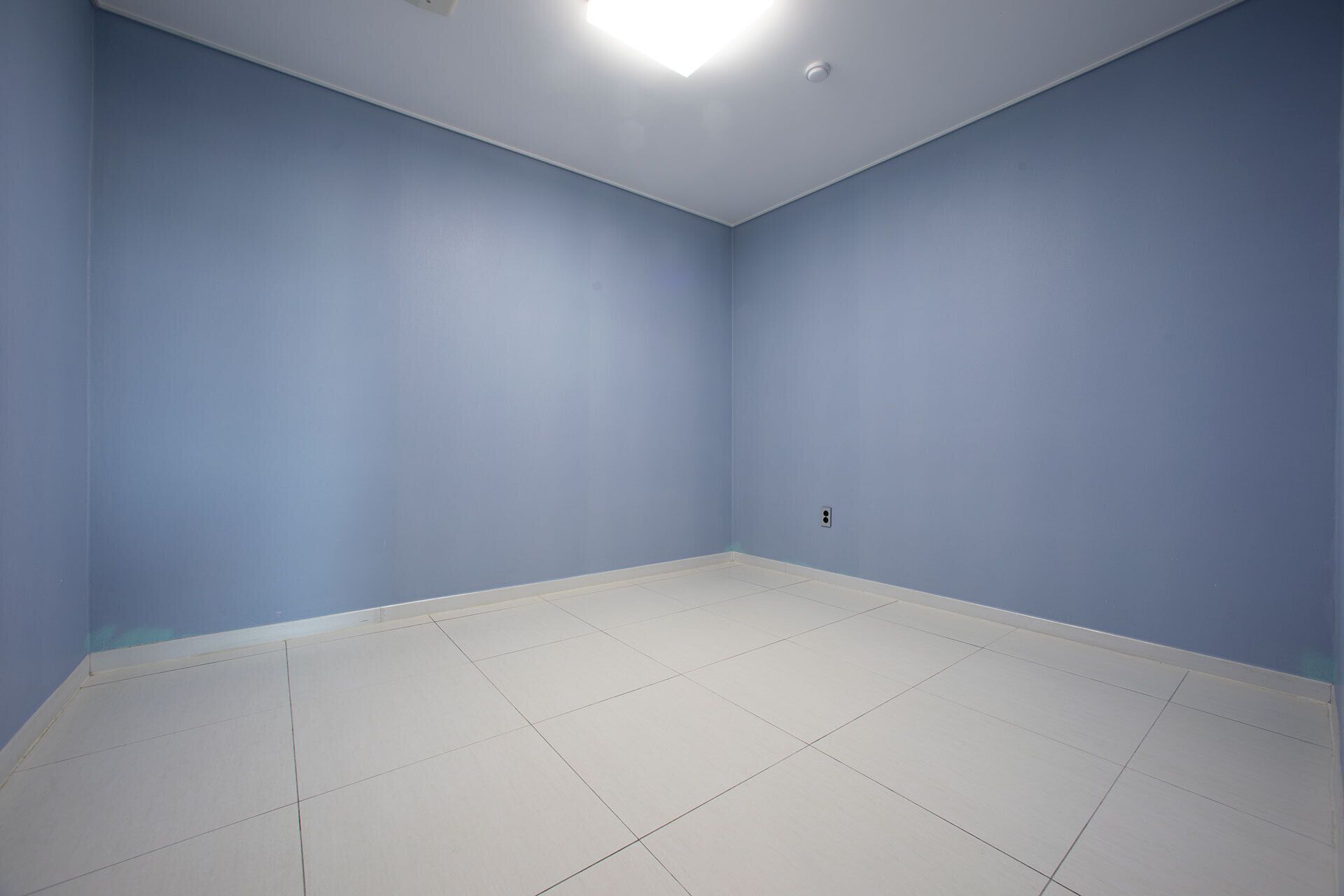 Een kamer met lichtblauwe wanden en witte betegelde vloer.