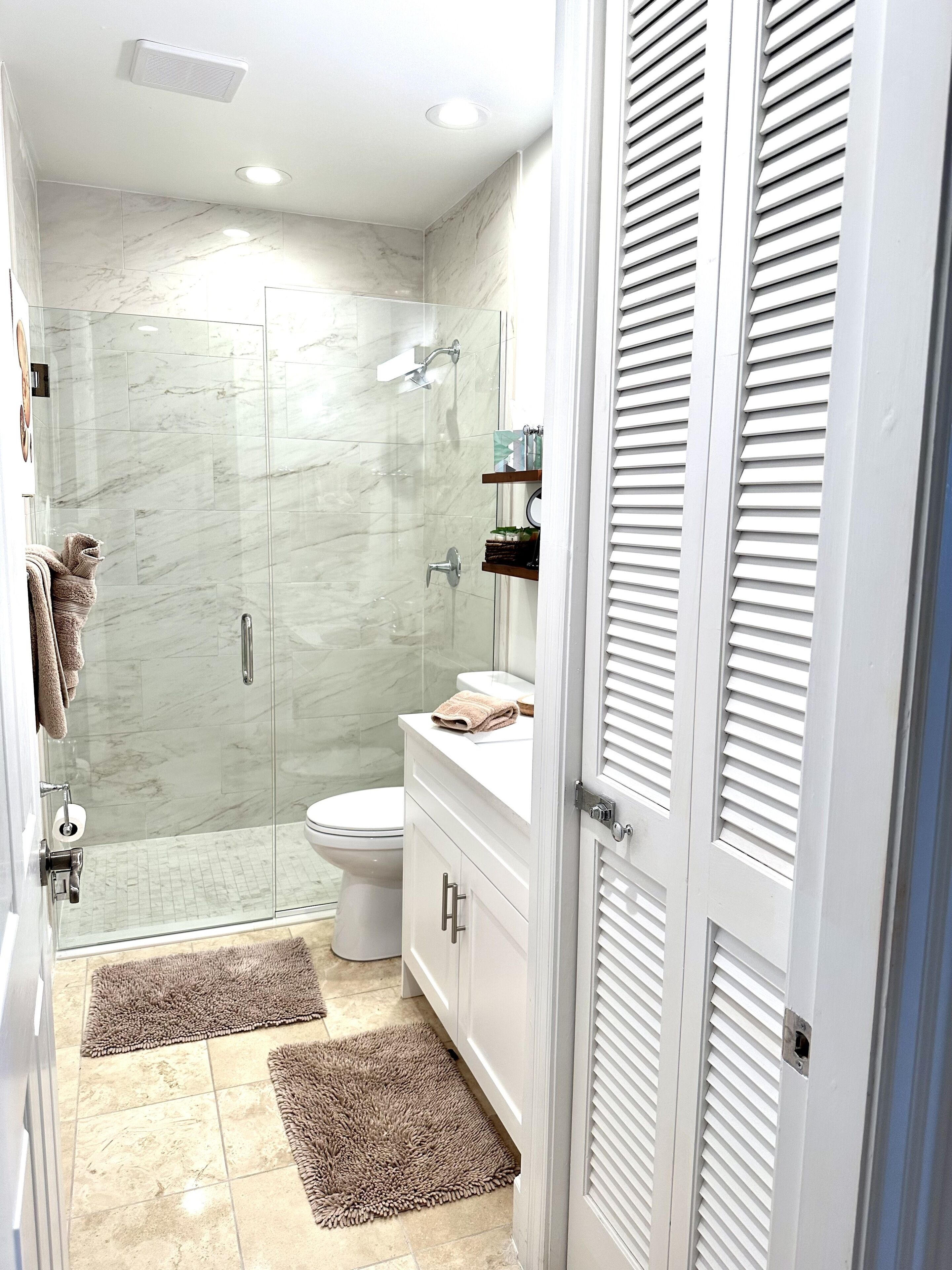 Een moderne badkamer met een douchecabine van glas, een toilet en een wastafel met spiegel.
