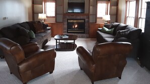 A living room with two leather sofas, a coffee table, and a fireplace. - Fantastic Large Home Right On Beautiful Lake Pepin!   (Lake City)
