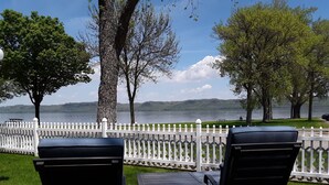 A lakeside view with a white picket fence, two black chairs, and a small table. - Fantastic Large Home Right On Beautiful Lake Pepin!   (Lake City)