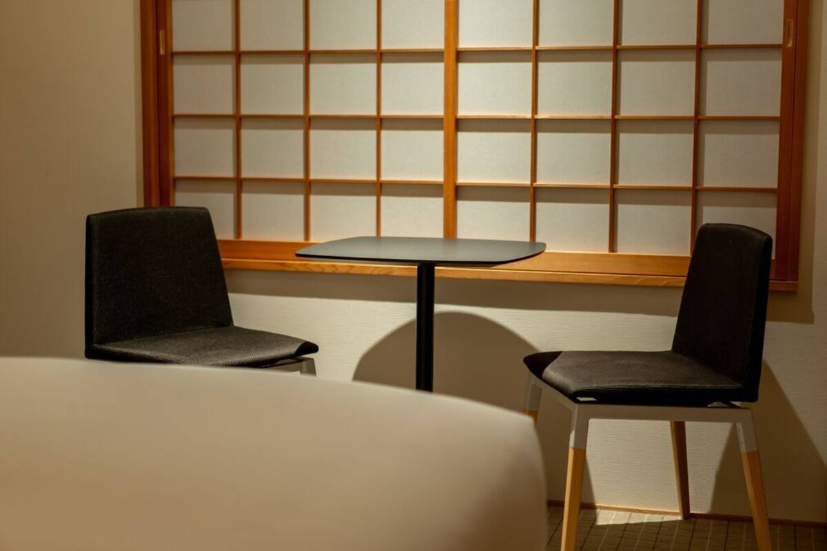 A room with a low table and two chairs, a window with a grid pattern, and a wooden frame.