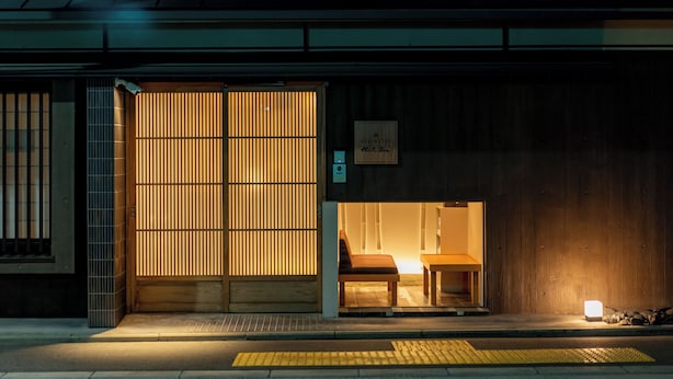 A traditional Japanese building with a sliding wooden door, a small seating area inside, and a sign indicating a 'RESERVATION' requirement. - RESI STAY Hachi Inn (Kyoto)