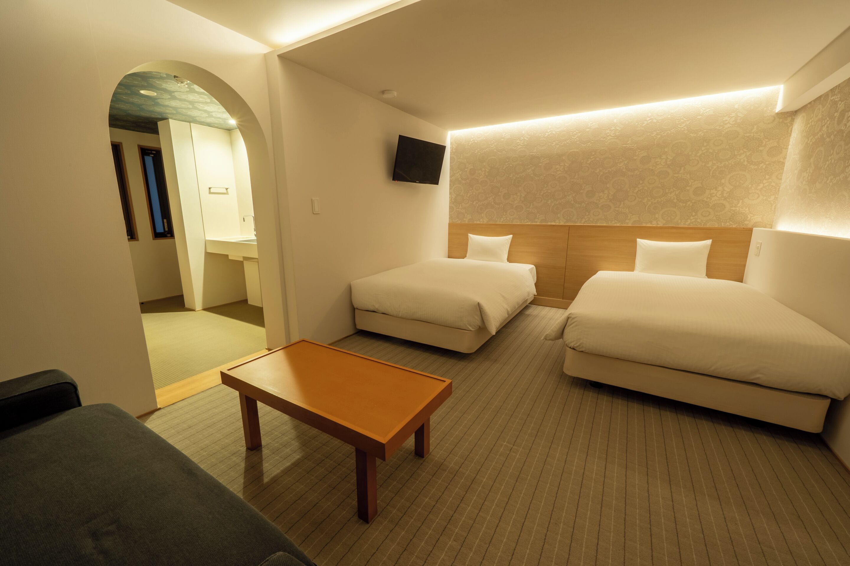 Een hotelkamer met twee bedden, een klein tafeltje en een televisie aan de muur.