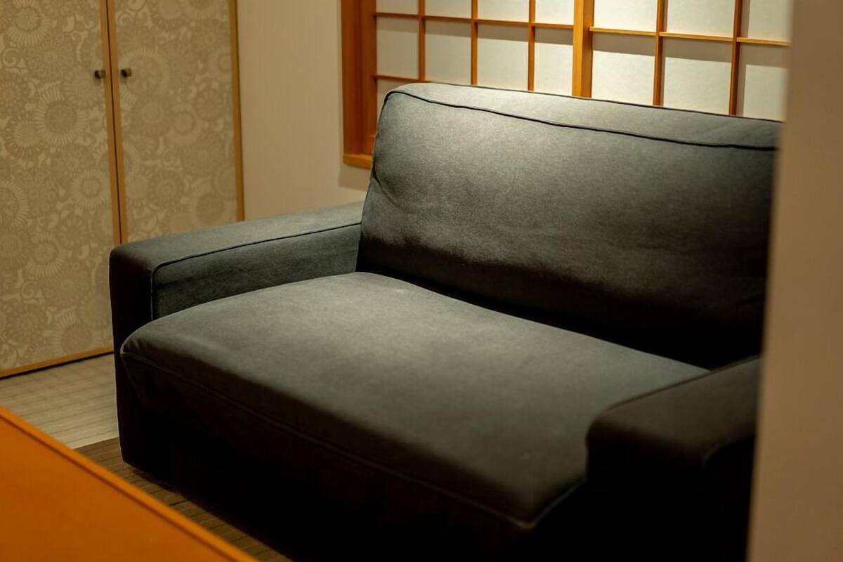 A dark-colored sofa in a room with a patterned wallpaper and a wooden sliding door.