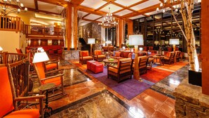 A spacious lobby with a stone fireplace, wooden furniture, and a large chandelier.