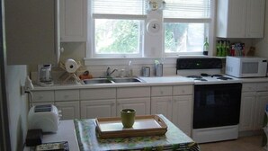 A kitchen with white cabinets, a stove, a microwave, and a sink.