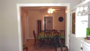 A dining area with a table set for four, surrounded by chairs. A ceiling fan is visible above the table.