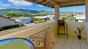 A balcony with a view of mountains, a chair, a table, and a potted plant.