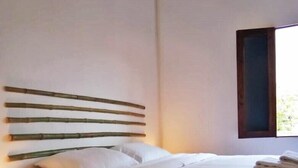 Un lit bien fait, avec du linge de lit blanc, une tête de lit en bois et une lampe de chevet.