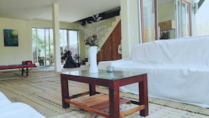 Un salon spacieux avec un canapé blanc, une table basse en bois et une grande fenêtre.