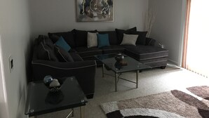 A modern living room with a sectional sofa, a coffee table, and a painting on the wall. - Newly renovated with lots of upgrades. (Portage)