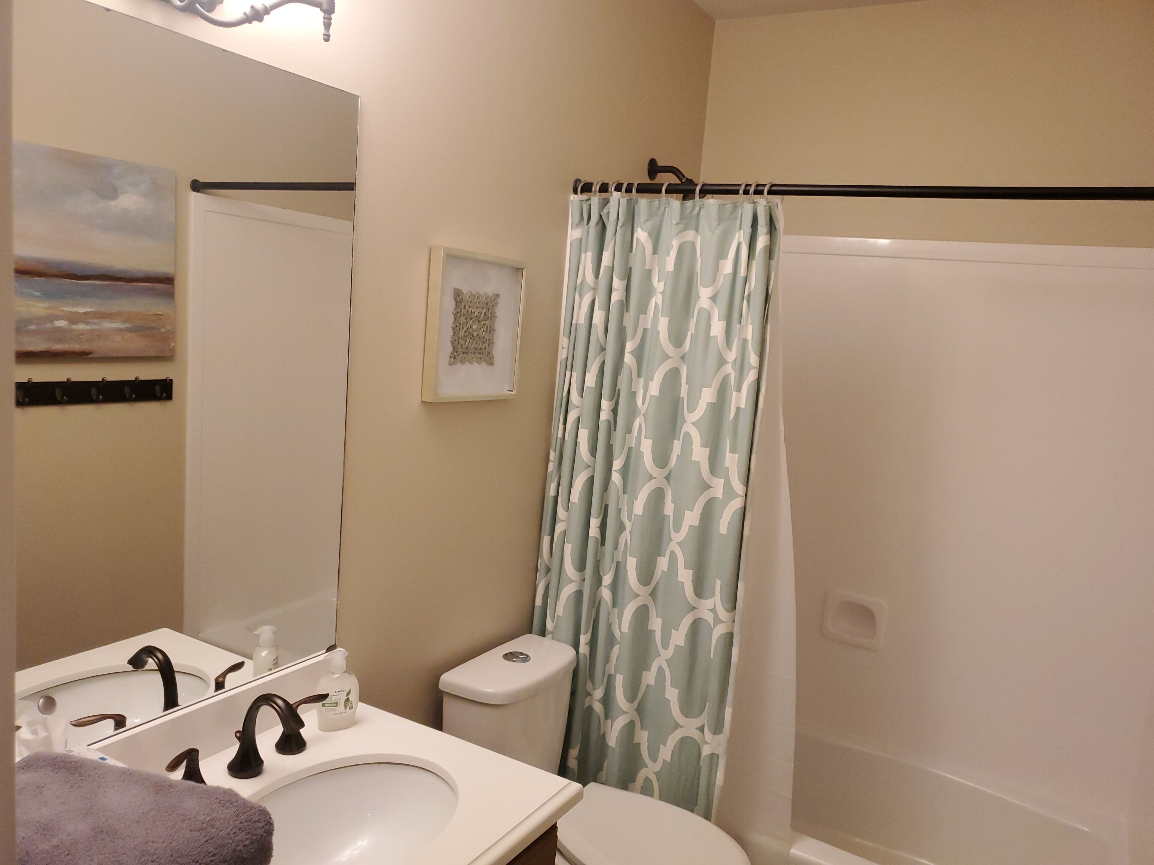 Une salle de bain avec un lavabo blanc, un miroir, des toilettes et un rideau de douche.