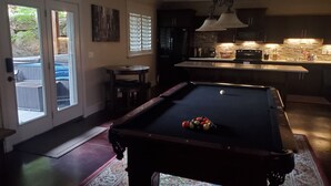 A pool table with balls, a dining area, and a kitchen with a bar. - Great Sandy apartment with hot tub and pool table! (Sandy)