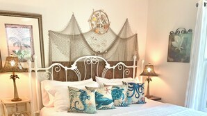 Een keurig opgemaakt bed met witte lakens, een decoratief hoofdbord en thematische kussens.