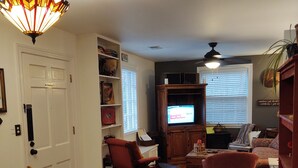 A cozy living room with a television, wooden furniture, and a bookshelf.