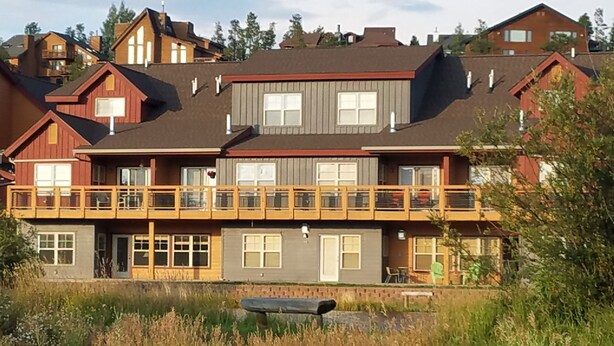 Ein mehrstöckiges Gebäude mit einer Holzterrasse und großen Fenstern.