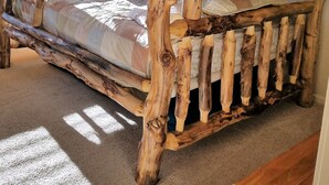 Ein schlichtes Holzbett mit Etagen, platziert in einem Raum mit schlichter Wand und einem Fenster mit Vorhängen.