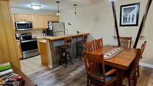 Eine Küche mit Holzausstattung, einer Mikrowelle, einem Kühlschrank und einem Essbereich mit einem Holztisch und Stühlen.