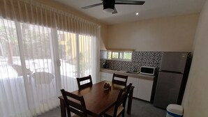 A dining area with a table and chairs, a kitchen with a microwave and refrigerator, and a ceiling fan. - Marysol edificio blanco depto 1 Isla Mujeres (Isla Mujeres)