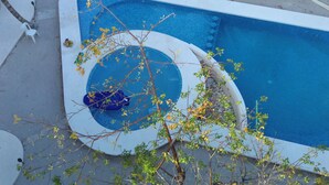 A swimming pool with a circular design, surrounded by a concrete deck and some greenery. - Marysol edificio blanco depto 1 Isla Mujeres (Isla Mujeres)