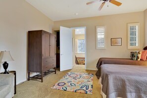 A bedroom with a bed, a wardrobe, a desk with a lamp, a patterned rug, and a ceiling fan.