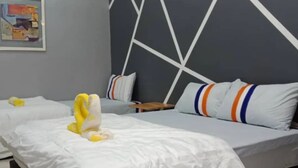 Habitación de hotel con dos camas, cada una con ropa blanca y almohadas de colores. Hay un cuadro en la pared y un patrón geométrico en la cabecera.