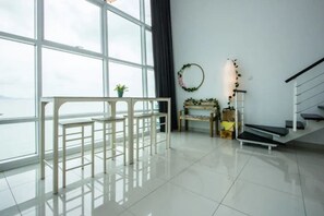 A spacious room with large windows, a white staircase, and a view of the sea. - Maritime Penang by SYNC (George Town)