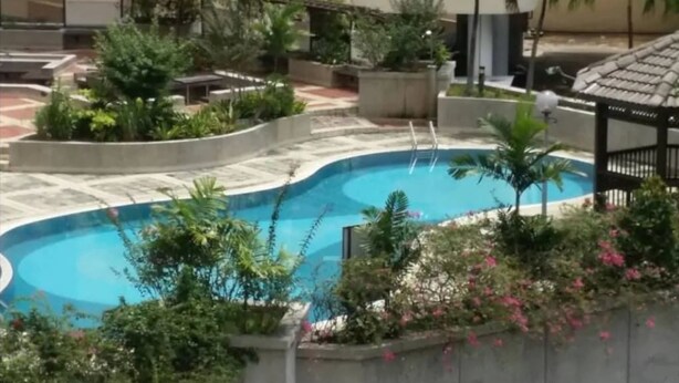 Une piscine entourée de verdure et un belvédère.