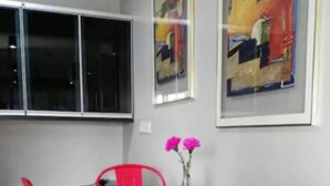 Un coin repas avec une table en bois foncé et quatre chaises rouges. Deux œuvres d’art encadrées sont accrochées au mur au-dessus de la table.