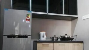 Une cuisine de taille réduite, dotée d’un réfrigérateur encastré, de meubles de rangement en bois et d’un four à micro-ondes.