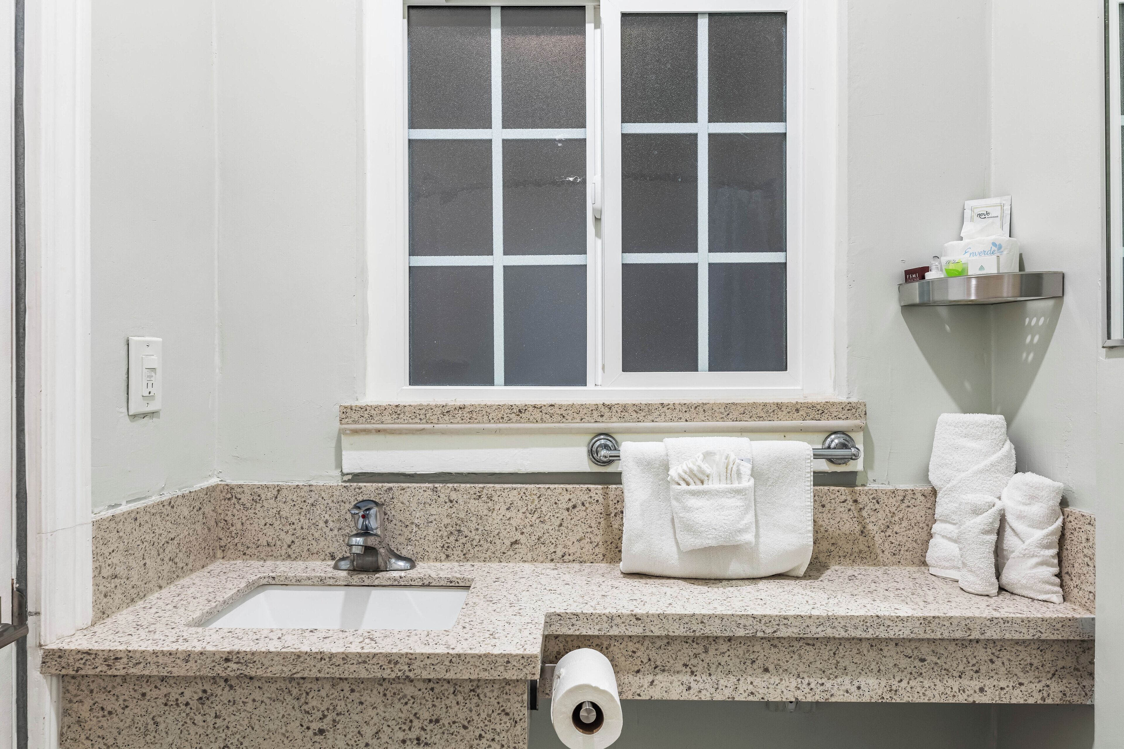 Baño con lavamanos, espejo, toallero y ventana.