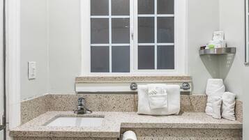 Baño con lavamanos, espejo, toallero y ventana.