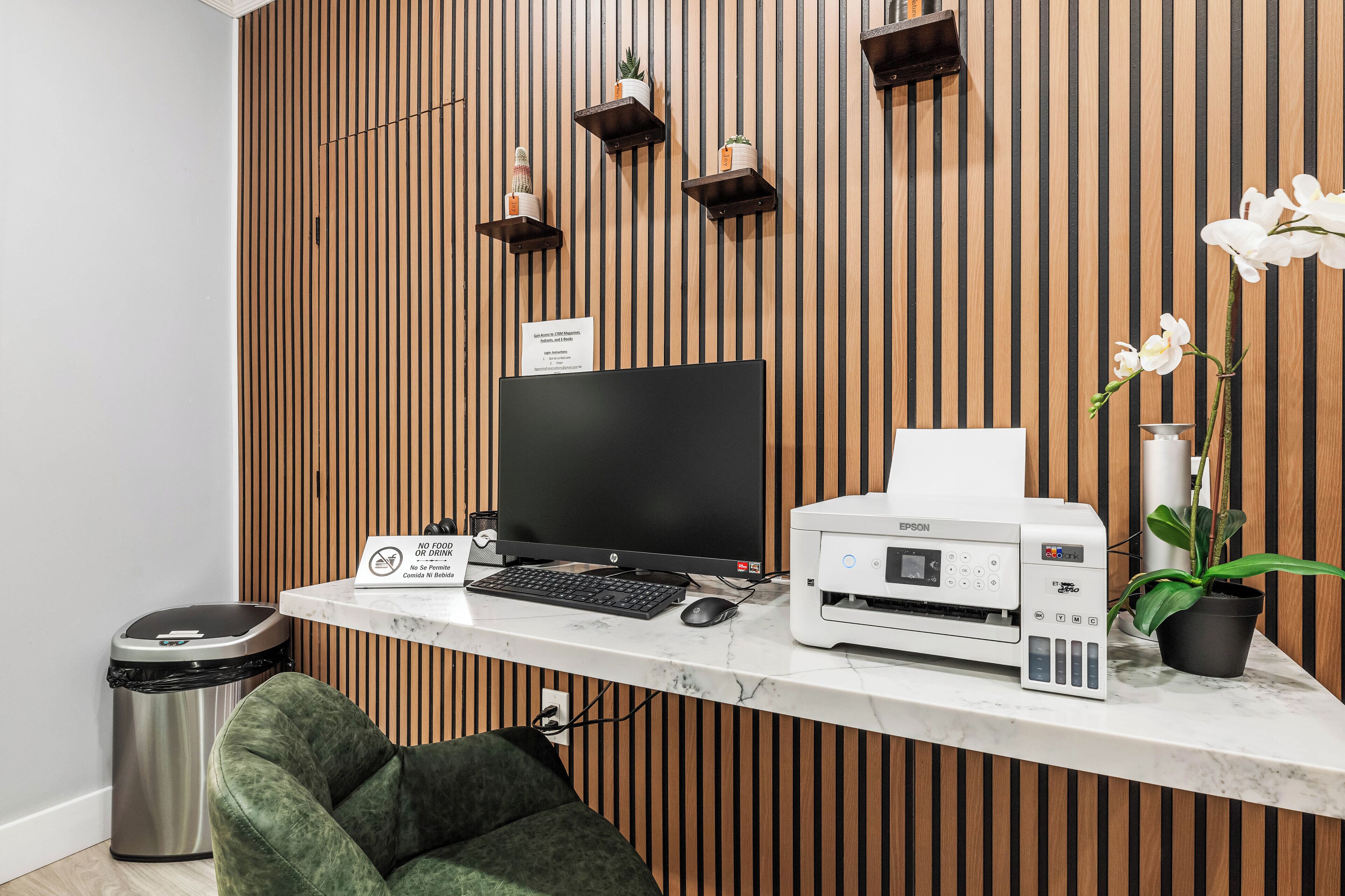 Uma mesa de recepção com computador, impressora e lixeira.