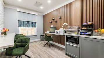 A modern kitchen with a wooden accent wall, a dining area with green chairs, and a window with curtains.